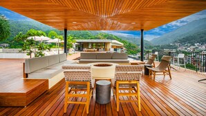A wooden deck with a sofa, chairs, and a fire pit. - Two Pools, Bar & Gym | Casa Medianoche at Oasis (Puerto Vallarta)