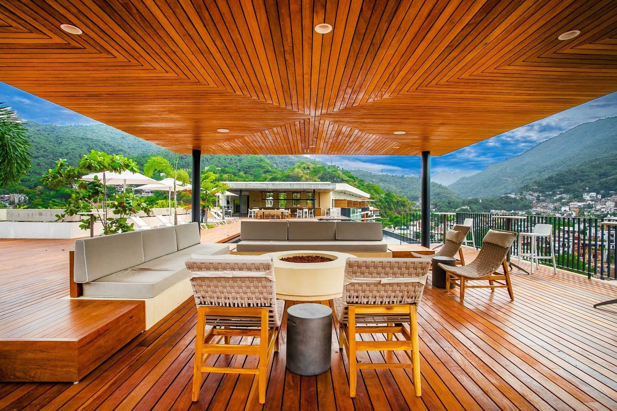 A wooden deck with outdoor seating, a fire pit, and a view of a mountainous landscape.