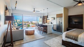 A modern apartment with a balcony, a kitchen, a dining area, and a bedroom. - Two Pools, Bar & Gym | Casa Medianoche at Oasis (Puerto Vallarta)