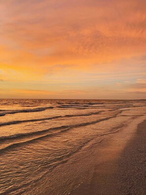 A beach with waves and a sunset.