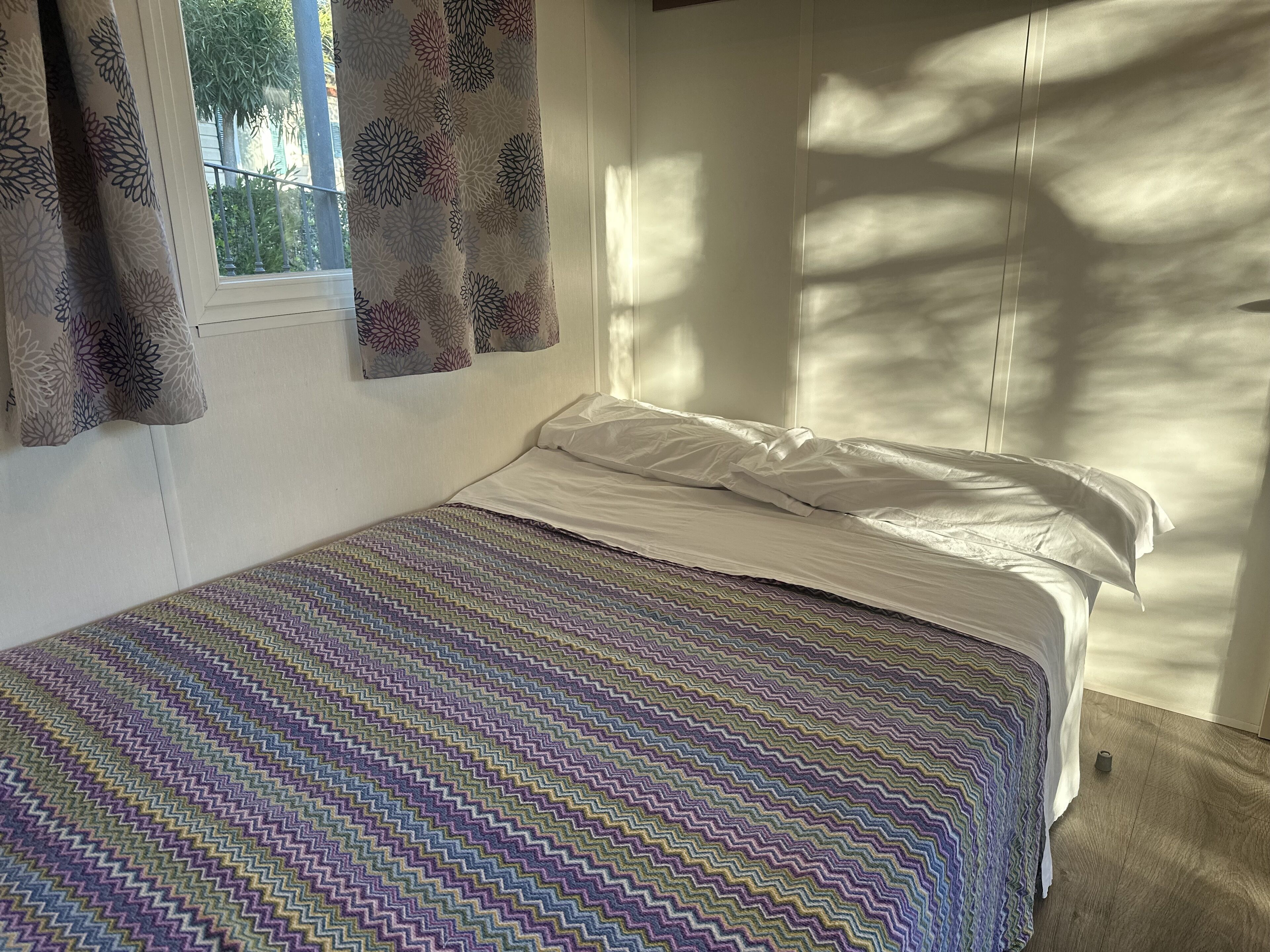 Une chambre à coucher avec un lit, des rideaux et une fenêtre.