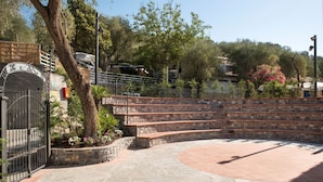 Un patio de piedra con un espacio abierto central, rodeado de escalones de piedra y una cerca de metal.