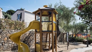 Un parque infantil con un tobogán amarillo y una estructura de juego de madera.