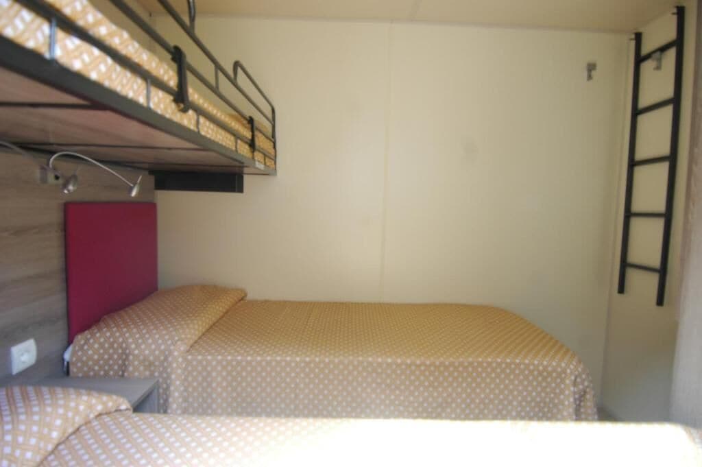 A bunk bed with a ladder, a red headboard, and a bed with a polka dot cover.