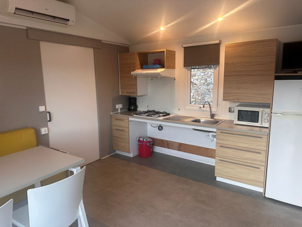 A compact kitchen with a gas stove, sink, microwave, and wooden cabinets.