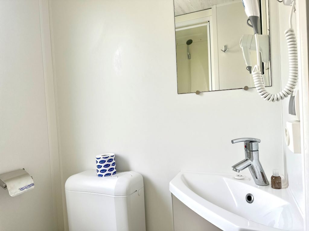Un baño con inodoro, lavamanos y espejo.