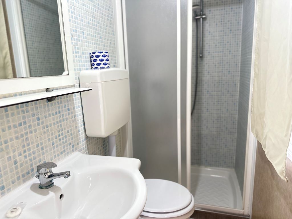 A bathroom with a white sink, a toilet, and a shower area.