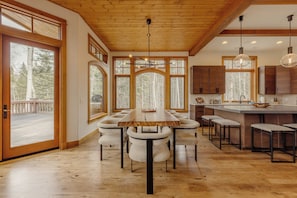 Una cocina amplia con una mesa y sillas de madera, ventanas grandes y vistas al exterior.
