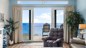 A living room with a view of the ocean, a leather armchair, a sofa, and a potted plant. - Gulf views w/ resort pools & beach access (Panama City Beach)