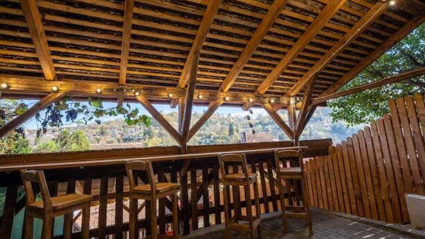 A wooden deck with a rustic ceiling and chairs, overlooking a scenic landscape. - Casa Maya Transylvania Studio (Sighișoara)