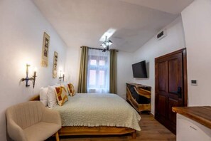 A bedroom with a bed, a chair, a TV, and a wardrobe. - Casa Maya Transylvania Studio (Sighișoara)