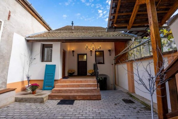 A building with a tiled roof, a wooden staircase, and a blue door.
