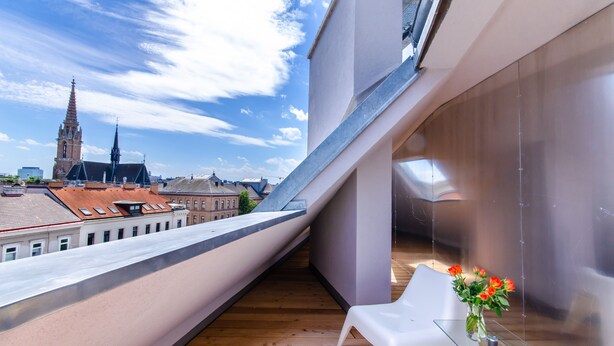 A modern balcony with a clear view of a historic church spire and surrounding buildings. - Grand Quarters City Residence (Vienna)