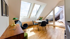 A modern dining area with a wooden table, black chairs, and a green vase with flowers. - Grand Quarters City Residence (Vienna)