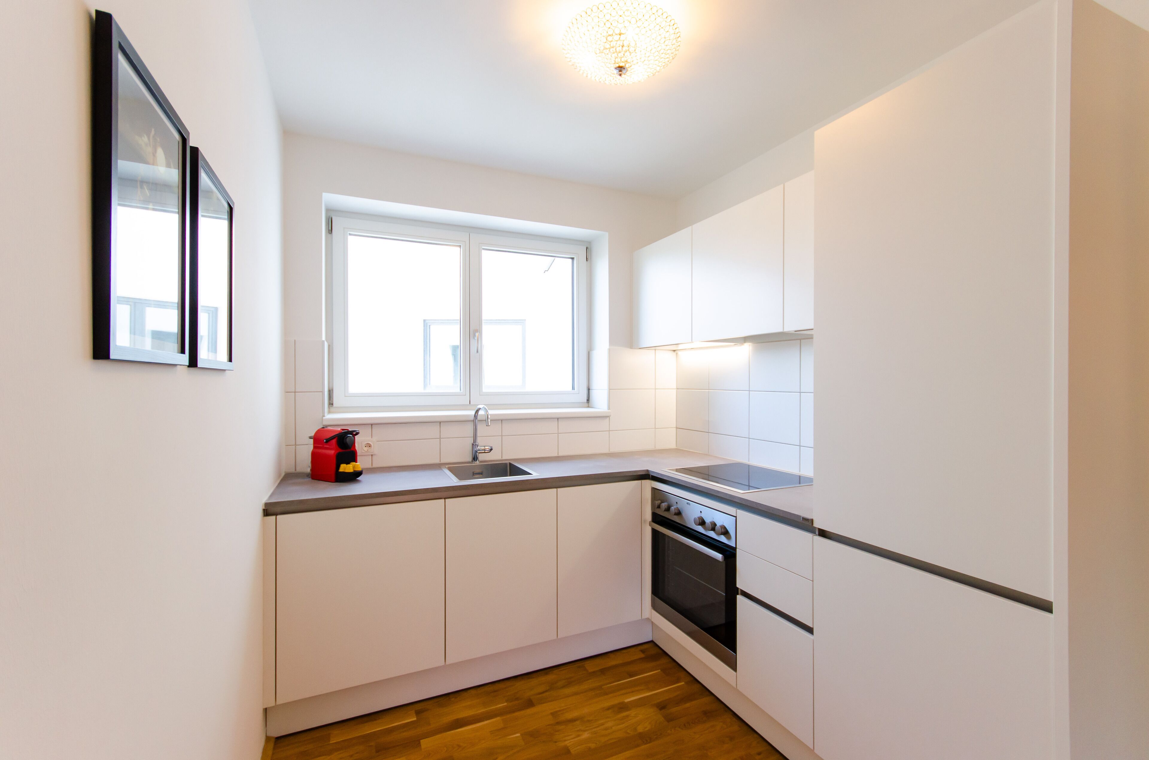 A compact kitchen with white cabinets, a double sink, and a built-in oven.