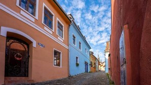 Une ruelle étroite pavée, bordée de bâtiments aux couleurs vives, dotés de portes et de fenêtres en arc de cercle.
