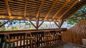 Une terrasse en bois, dotée d’un plafond rustique et de chaises, qui offre une vue imprenable sur un paysage magnifique.