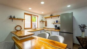 Une cuisine compacte dotée d’un plan de travail en bois, d’un réfrigérateur et d’une fenêtre laissant entrer la lumière naturelle.