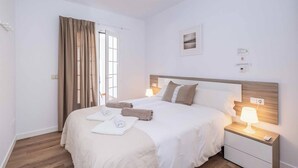 Una habitación de hotel con una cama grande, dos mesitas de noche con lámparas, una ventana con cortinas y un cuadro colgado en la pared.