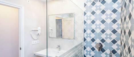 A modern bathroom with a glass-enclosed shower, a white sink, and a mirror above it.