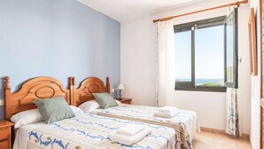 A double room with two beds, a wooden headboard, a nightstand, a lamp, and a window with a view. - Es Llaut - Three Bedroom Villa, Sleeps 6 (Binibeca)