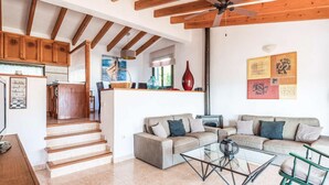 A spacious living area with a sofa set, a glass coffee table, and a staircase leading to an upper level. - Es Llaut - Three Bedroom Villa, Sleeps 6 (Binibeca)