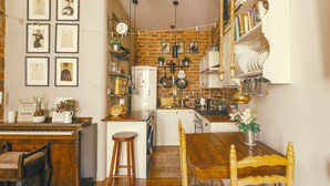 A cozy kitchen with a piano, wooden dining table, and various kitchen utensils.