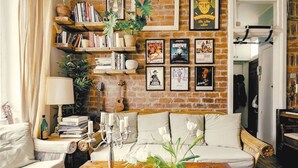 A cozy living room with a brick wall, a sofa, a coffee table, and various framed pictures and books.