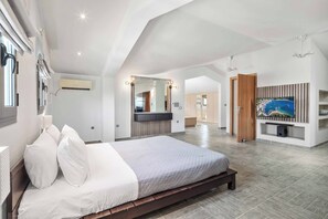 A modern bedroom with a large bed, a vanity with mirrors, and a TV mounted on the wall.