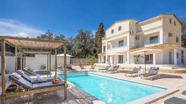 Area piscina con lettini, un pergolato e un edificio a due piani con balconi.