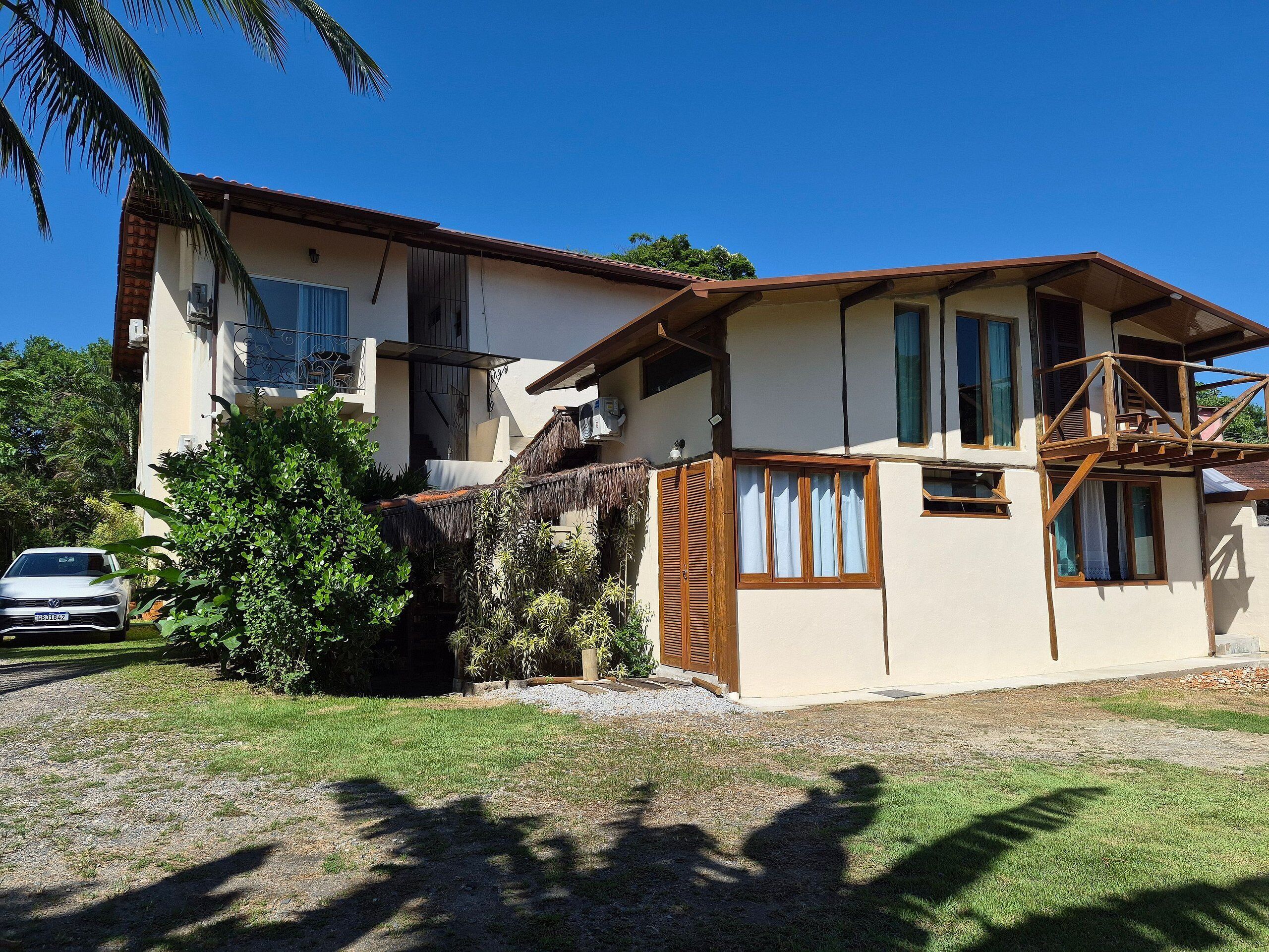A two-story house with a balcony, a car parked in the driveway, and a well-maintained lawn.