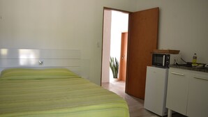 A bedroom with a bed, a microwave, and a small cabinet. - Plus Couple Suite with mini kitchen (Ilhabela)