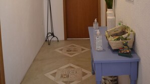 Ein Flur mit einer Holztür, einem blauen Tisch mit Toilettenartikeln, einer hohen Stehlampe und einem gemusterten Teppich.