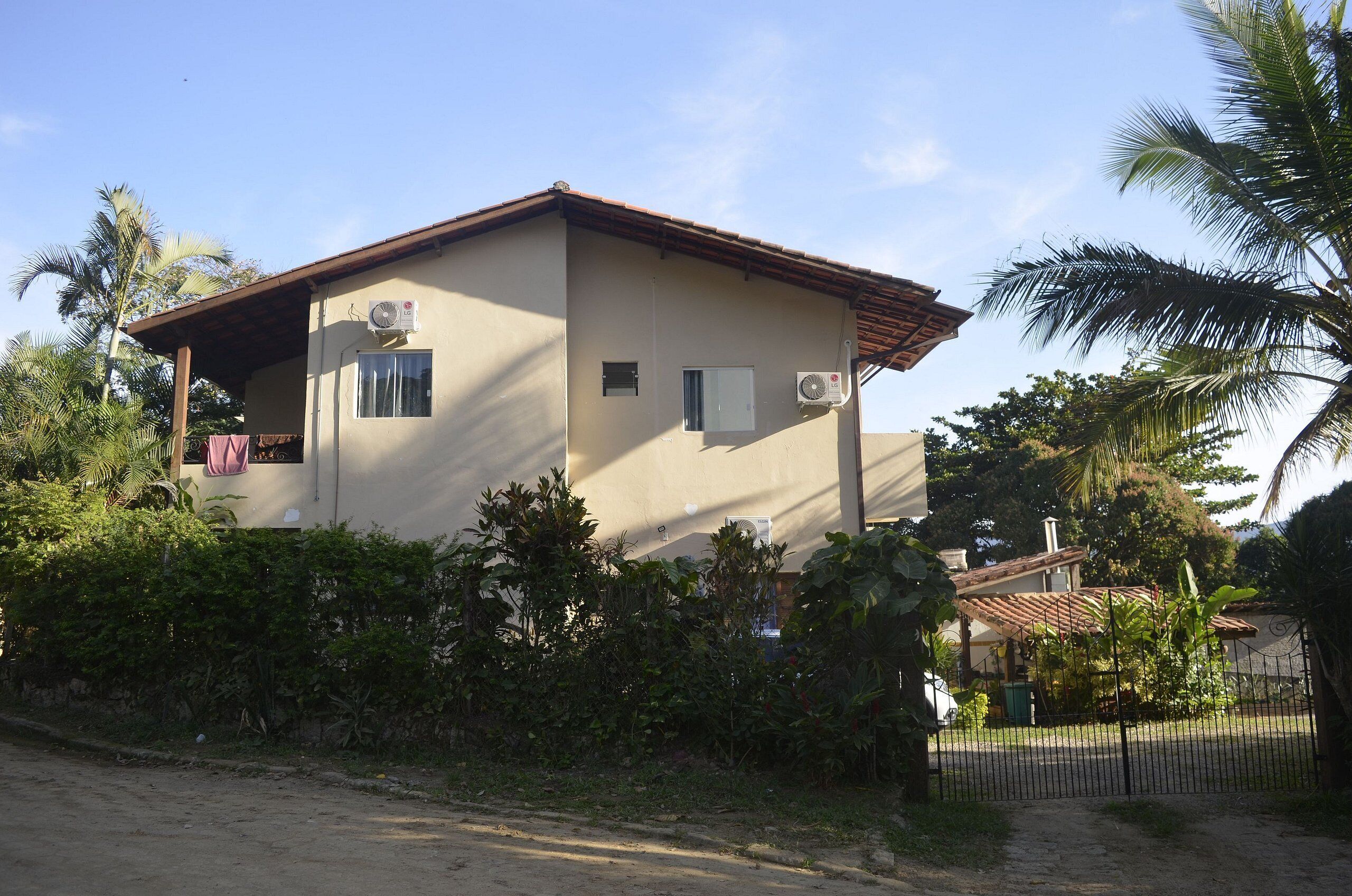 Una casa de dos pisos con techo plano, unidades de aire acondicionado y una ventana pequeña.