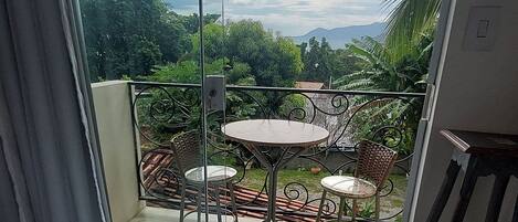 A balcony with a glass door, a round table, and two chairs.