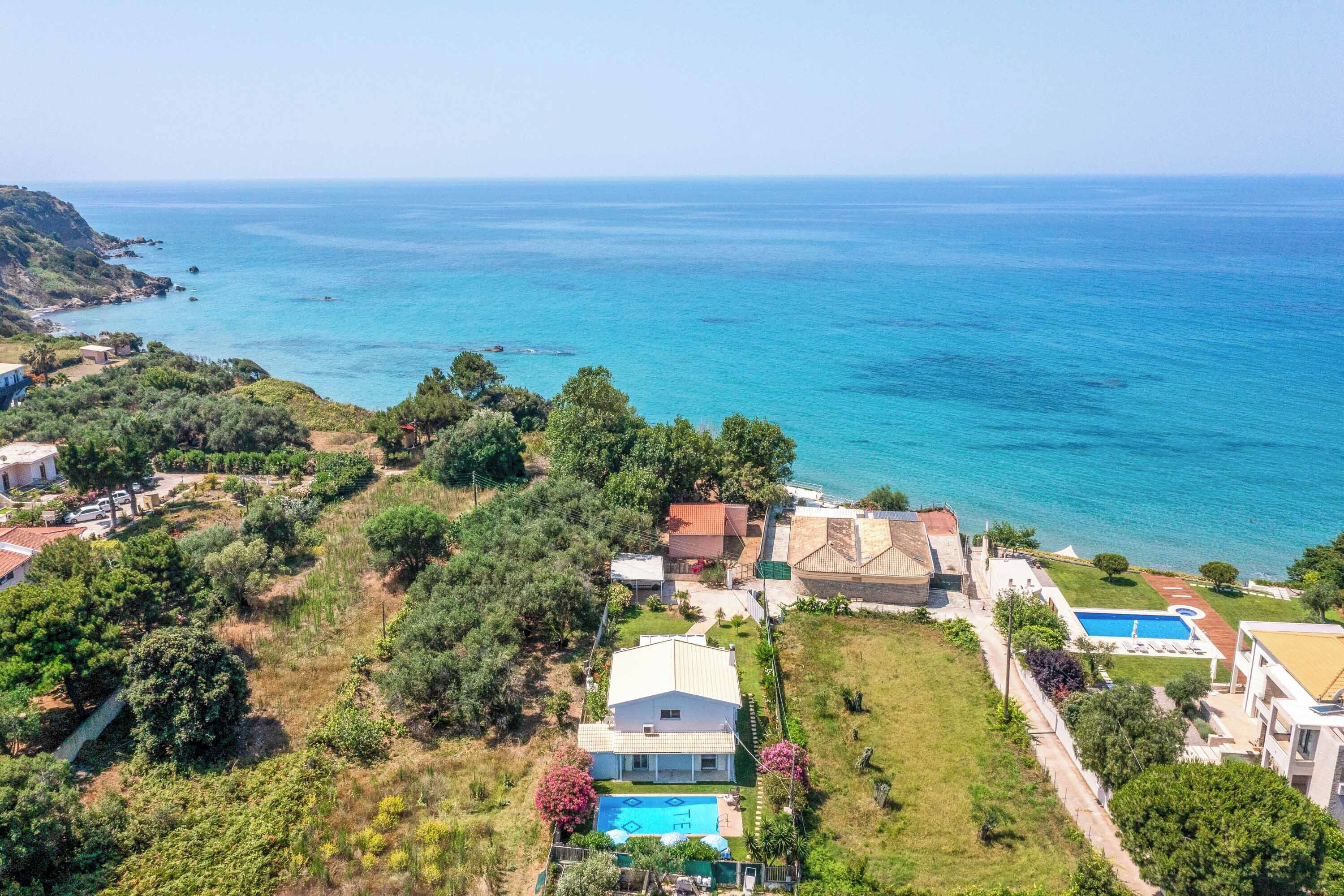 A coastal property with a swimming pool, a large house, and a view of the sea.
