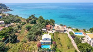 An aerial view of a coastal property with a swimming pool, lush greenery, and a clear view of the sea. - Villa Teo - Four Bedroom Villa, Sleeps 8 (Ionian Islands)
