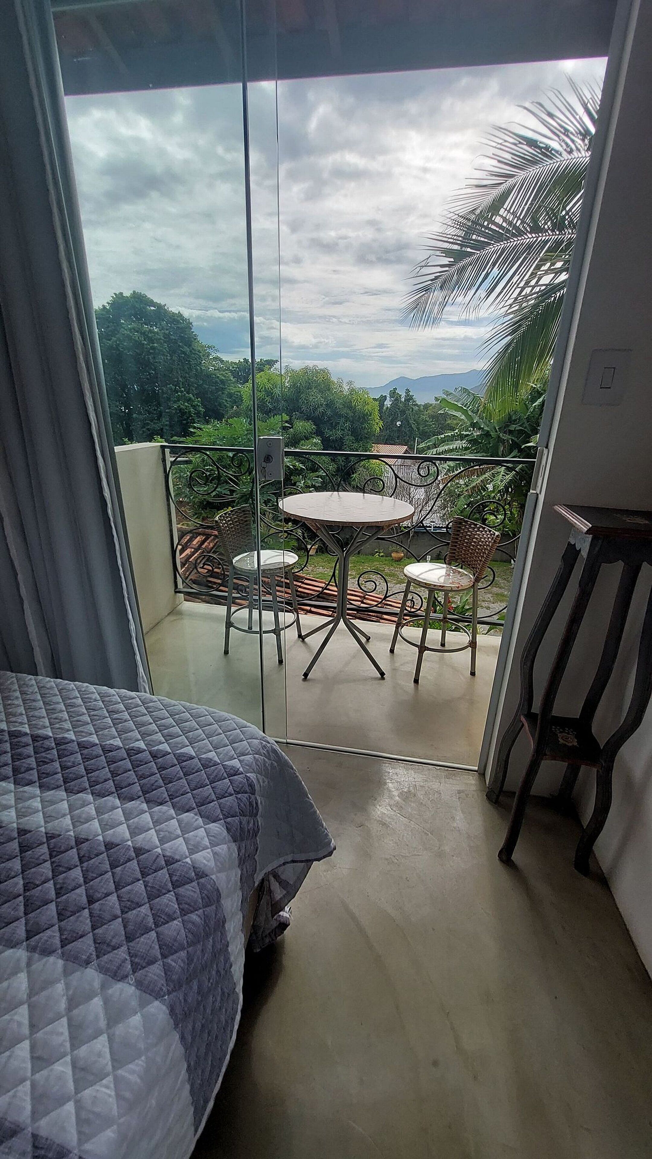 Ein Balkon mit Glastür, einem runden Tisch und zwei Stühlen.
