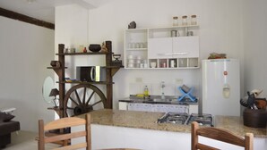Une cuisine avec une chaise en bois, une table à manger et un réfrigérateur blanc.