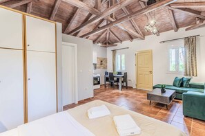 A spacious room with a bed, a green sofa, a dining area, and a kitchen. - Villa Palataki II - One Bedroom Villa, Sleeps 2 (Ditiki Mani)