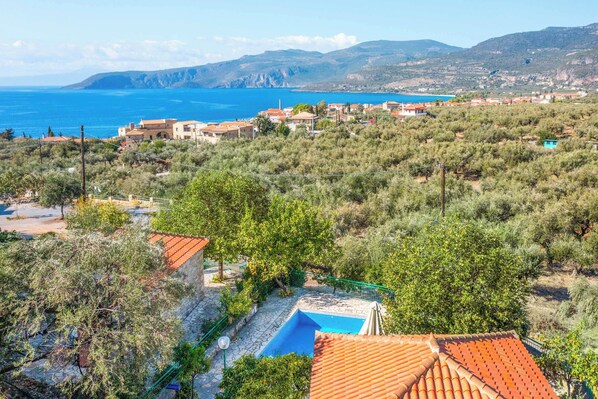Un pueblo costero con casas escalonadas, una piscina y vistas al mar.