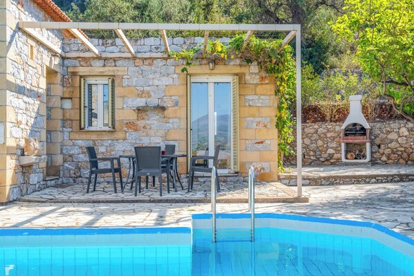 Un edificio de piedra con piscina, mobiliario de exterior y zona de barbacoa.