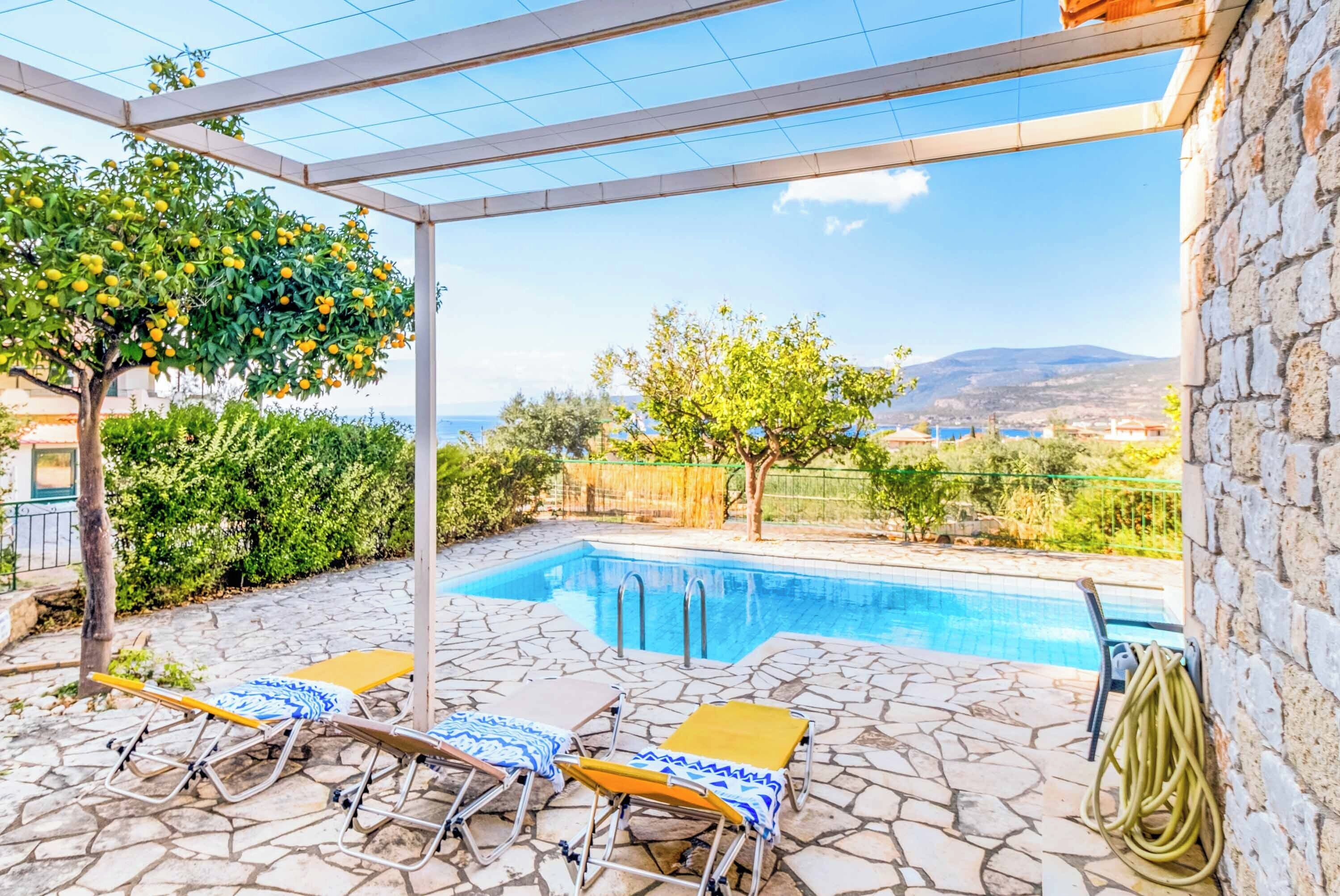 Area piscina con pavimento in pietra, due sdraio e un gazebo con vista sul mare.
