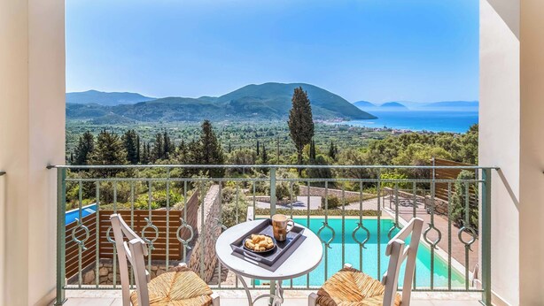 A balcony with a table and chairs, overlooking a swimming pool and a scenic view of mountains and the sea. - Villa Ira Lefkas - One Bedroom Villa, Sleeps 2 (Lefkada)