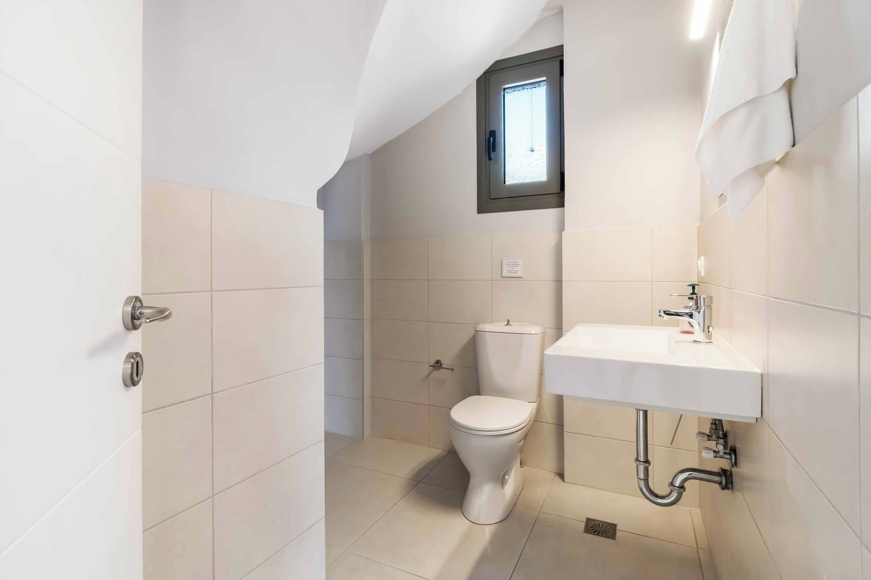 Un bagno piccolo e moderno con un WC, un lavandino e una finestra sopra il WC.