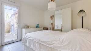Ein Schlafzimmer mit Bett, Schminktisch, Spiegel und einer Tür, die zu einem Außenbereich führt.