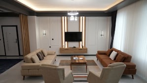 A modern living room with two sofas, a coffee table, and a TV on a wooden stand. - Villa Kent Termal Otel (Ihsaniye)
