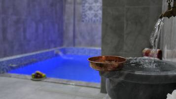A copper bowl on a stone pedestal with water flowing from a tap.