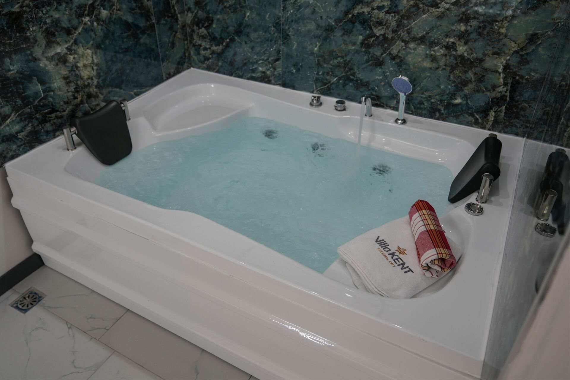 A bathtub with a marble wall background.