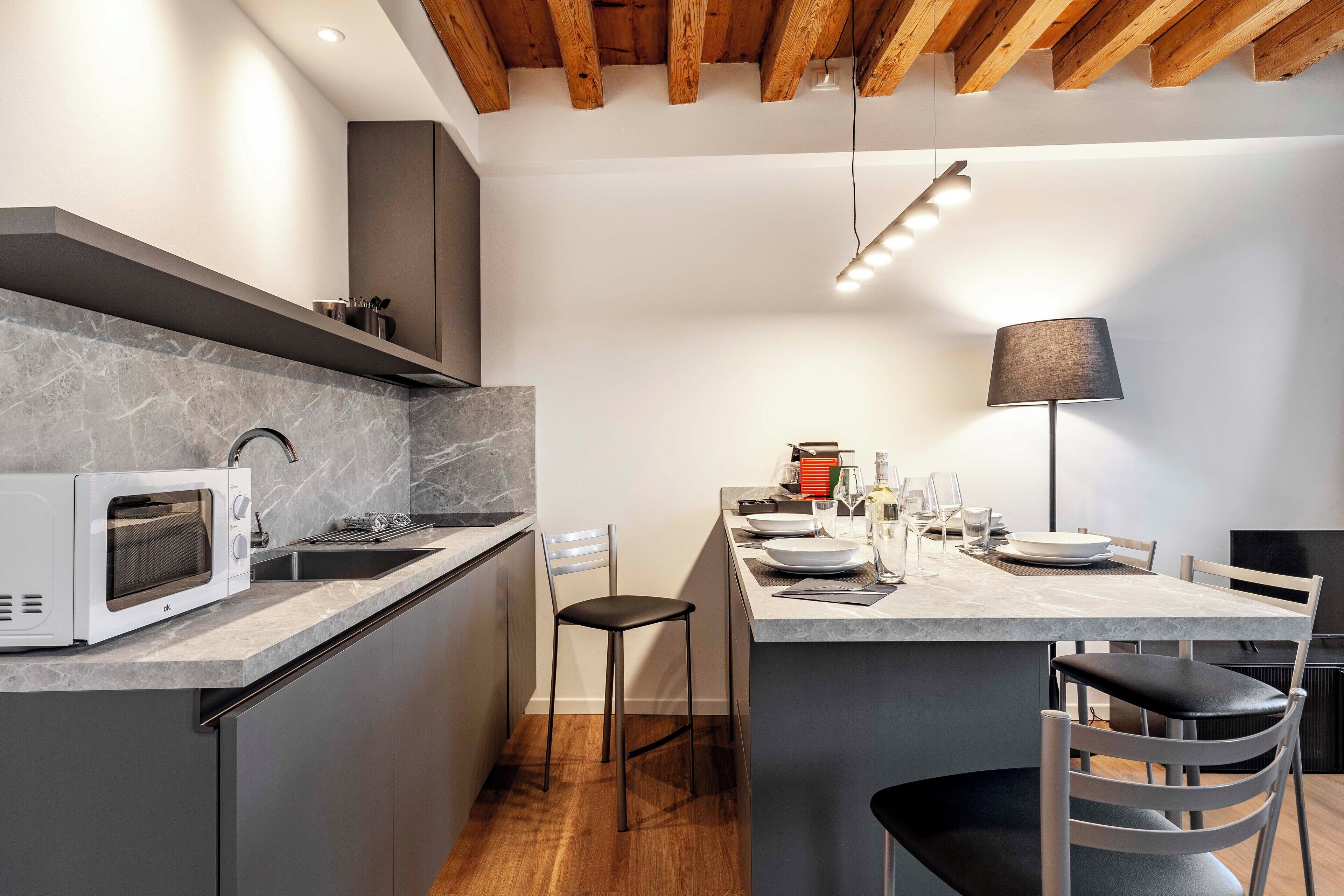 Uma cozinha moderna com micro-ondas embutido, pia e área de jantar com mesa e cadeiras.